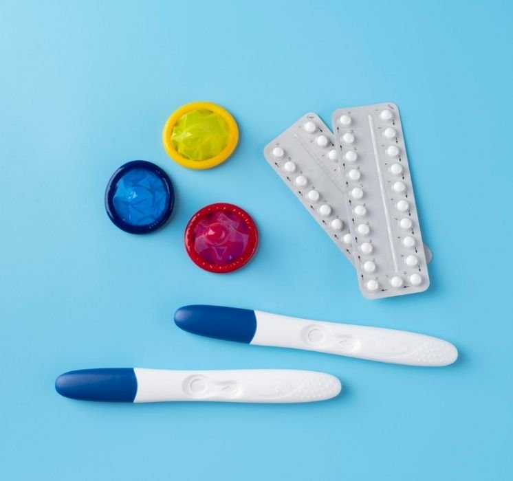 Préservatifs, plaquettes de pilules contraceptives et tests de grossesse sur fond bleu pour l'atelier de santé sexuelle avec Pluri-elles.