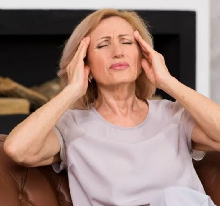 Femme d'âge mûr exprimant des symptômes de la ménopause comme des maux de tête ou bouffées de chaleur avec Pluri-elles
